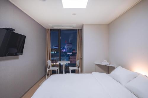 a hotel room with a bed and a table and a window at 벨라 레지던스 in Chuncheon