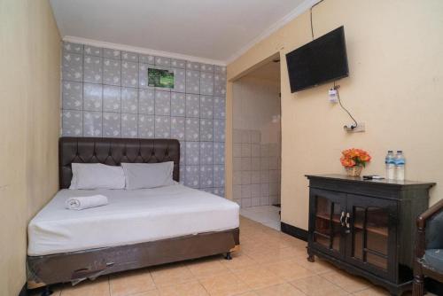 ein Schlafzimmer mit einem Bett und einem TV an der Wand in der Unterkunft Sabar Mansion 22 Mitra RedDoorz in Jakarta
