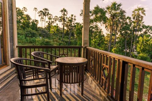 un porche con 2 sillas y una mesa en el balcón en Coral Bay Bungalows Amed Bali, en Amed