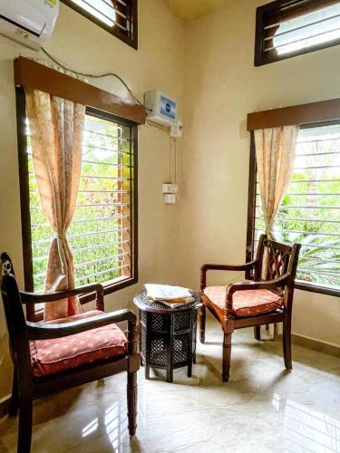 a living room with two chairs and two windows at Namdang Homestay in Sibsāgar