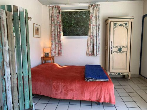 a bedroom with a red bed and a window at Maison Pleumeur-Bodou, 1 pièce, 4 personnes - FR-1-368-395 in Pleumeur-Bodou