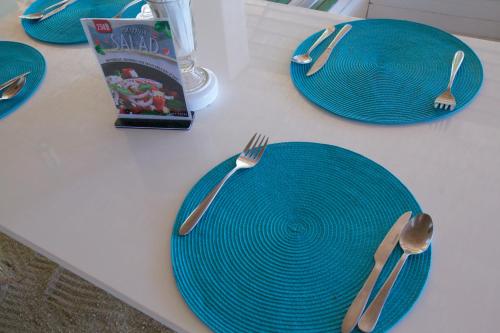 a table with blue plates and forks and a book at Lime N Soda Beachfront Resort in Thongsala