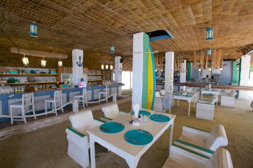 a restaurant with a table and chairs and a surfboard at Lime N Soda Beachfront Resort in Thongsala