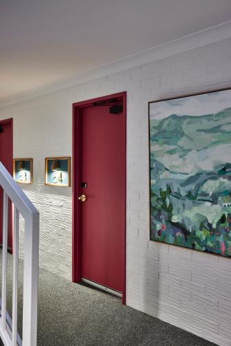 a red door in a room with a painting on the wall at Central Caleula Motor Lodge in Orange