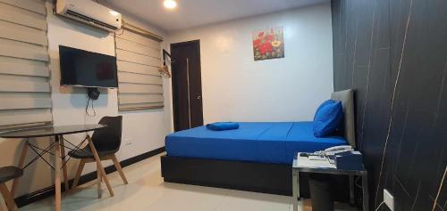 a small room with a blue bed and a table at Maine City Residences in Manila