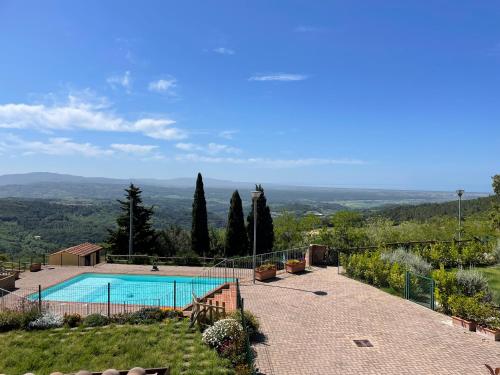 a swimming pool on top of a hill with trees at Casa Lisa Poggio di Nocola Riparbella by ToscanaTour in Podere Dottrina