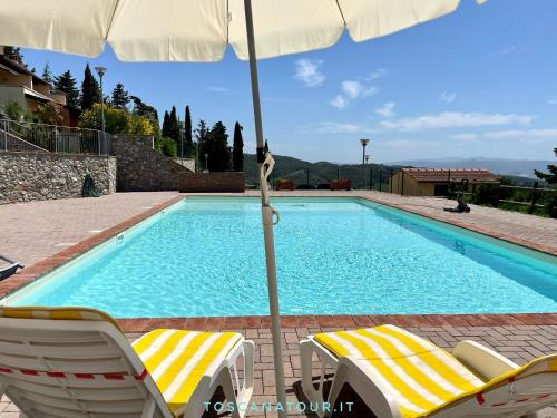 a swimming pool with two chairs and an umbrella at Casa Lisa Poggio di Nocola Riparbella by ToscanaTour in Podere Dottrina