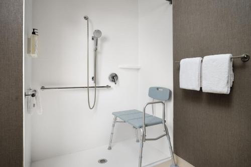 y baño con ducha y silla azul. en SpringHill Suites Kansas City Overland Park, en Overland Park