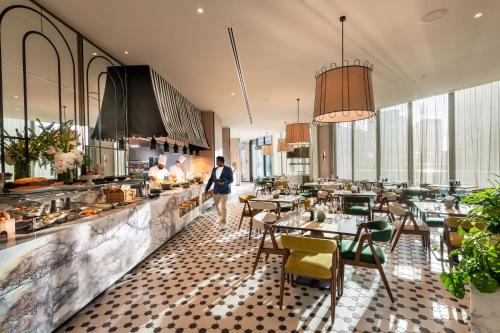 a man walking through a restaurant with tables and chairs at Dorsett Melbourne in Melbourne