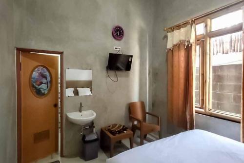 a bedroom with a bed and a sink and a window at Sukawana Guest House Mitra RedDoorz 
