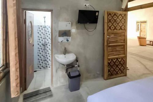 a bathroom with a sink and a tv on the wall at Sukawana Guest House Mitra RedDoorz 