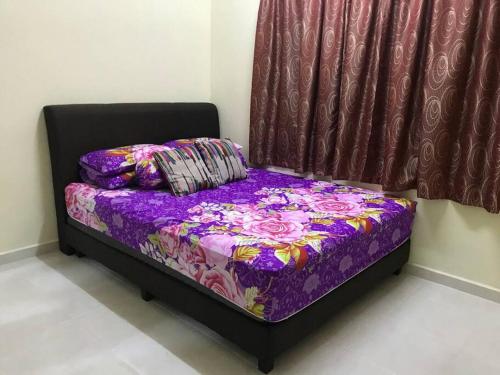 un lit avec une couette et des oreillers violets à côté d'une fenêtre dans l'établissement Hajjah Homestay Asun, Jitra, Alor Setar Kedah, à Jitra