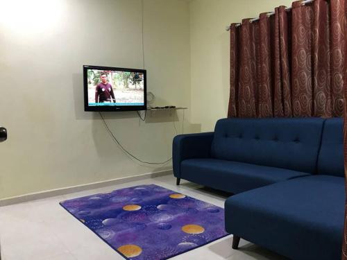 un salon avec un canapé bleu et une télévision dans l'établissement Hajjah Homestay Asun, Jitra, Alor Setar Kedah, à Jitra