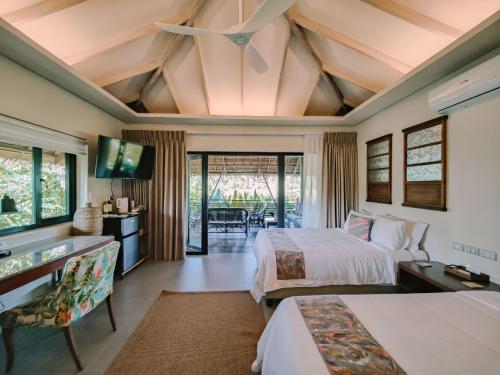 a hotel room with two beds and a television at Kaimana Resort Siargao in General Luna
