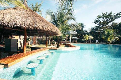 una piscina con sillas y una sombrilla de paja en Eco Glamping Treehouses Closest Resort To All Tourist Attractions, en Balilihan
