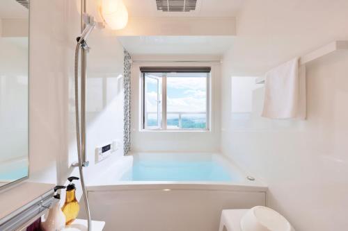uma casa de banho branca com uma banheira e uma janela em Crystal Exe Nanki Shirahama 1 em Shirahama