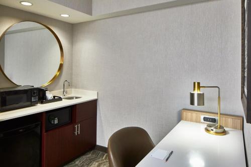 a bathroom with a sink and a table with a mirror at SpringHill Suites Memphis Downtown in Memphis