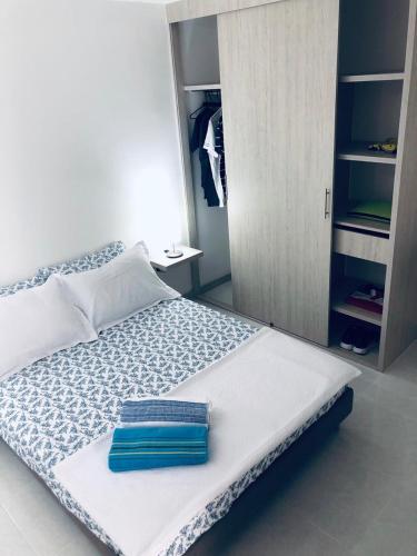 a white bed with a blue towel on it at Apartamento Armenia a 15 min del Parque del Café in Armenia