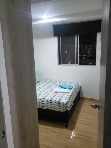 um pequeno quarto com uma cama e uma janela em shared -compartido- apartment in a quiet, secure and lovely apartment em Sabaneta