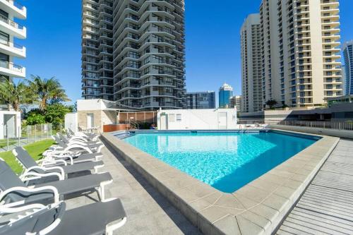 a swimming pool with lounge chairs and buildings at Spectacular Central Surfers Beach Views from Apartment in Gold Coast