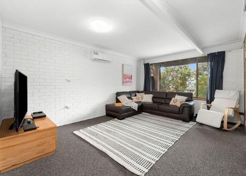 a living room with a couch and a tv at Park and Relax in Surf Beach