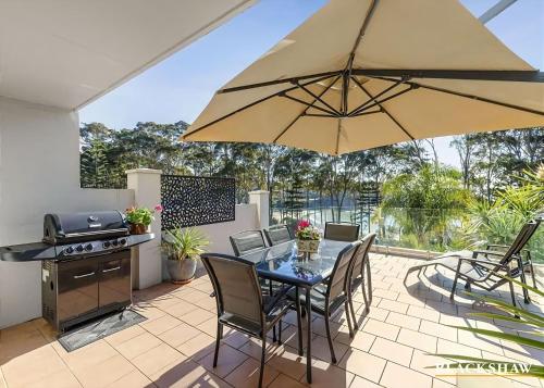 a patio with a table with chairs and an umbrella at Seaview by the Cliff in Surf Beach