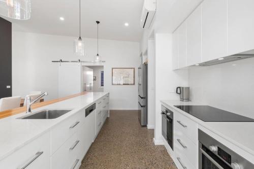 a white kitchen with a sink and a refrigerator at Bada Bliss in Tomakin