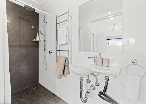 a white bathroom with a sink and a shower at Cloud 9 at Batehaven in Batehaven
