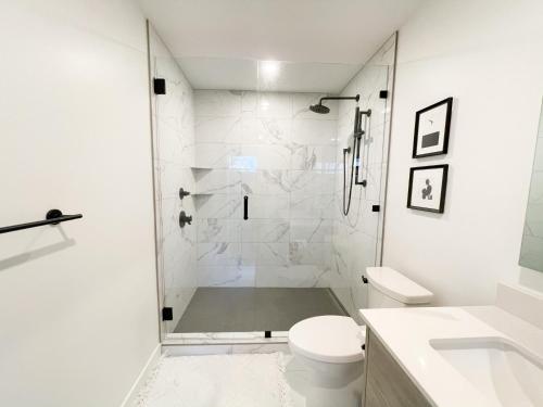 a white bathroom with a shower and a toilet at *NEW* HAVN HOUSE MODERN RETREAT - STEPS FROM BEACH in Penticton
