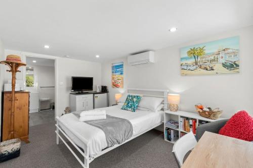 1 dormitorio con 1 cama, escritorio y TV en Tomaga Tides, en Mossy Point