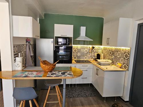 uma cozinha com armários brancos e uma mesa de madeira em Le 134 Arles Centre climatisé 1 à 4 personnes Appartement em Arles