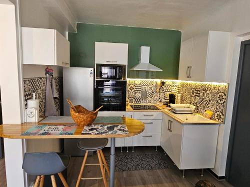 a kitchen with white cabinets and a wooden table at Le 134 Arles Centre climatisé 1 à 4 personnes Appartement in Arles