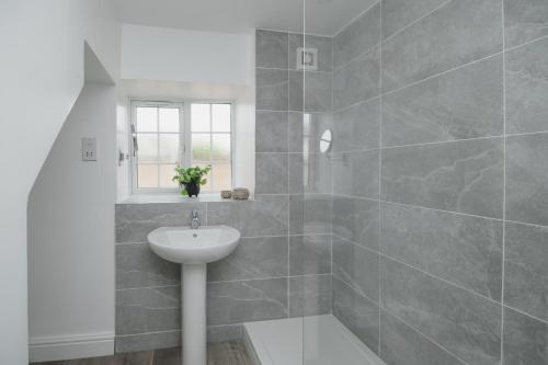 baño blanco con lavabo y ventana en Lovely Stone Cottage In The Heart Of Adderbury, en Adderbury