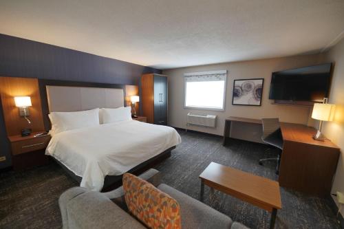 a hotel room with a bed and a desk and a tv at Holiday Inn & Suites Chicago-Carol Stream Wheaton by IHG in Carol Stream
