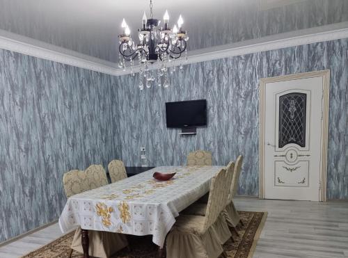 a dining room with a table and a chandelier at Deluxe in Shymkent