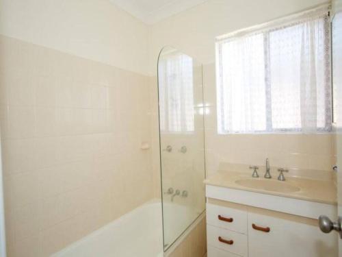 a white bathroom with a shower and a sink at Ocean view beachside 3 bedroom 2 bathroom unit in Caloundra