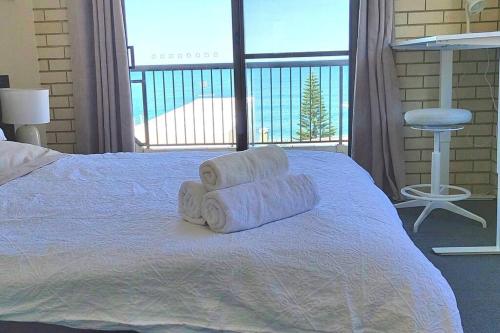 two towels on a bed with a large window at Ocean view beachside 3 bedroom 2 bathroom unit in Caloundra