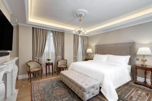 a bedroom with a large white bed and a fireplace at King George, a Luxury Collection Hotel, Athens in Athens