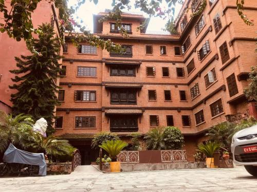 a large brick building with trees in front of it at Courtyard Pujan Hotel in Kathmandu