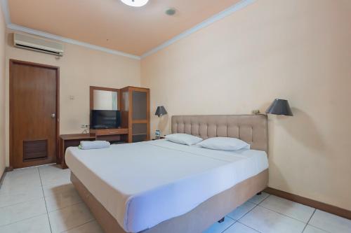 a bedroom with a large white bed and a television at Dequr Hotel Dipati Ukur Mitra RedDoorz in Bandung