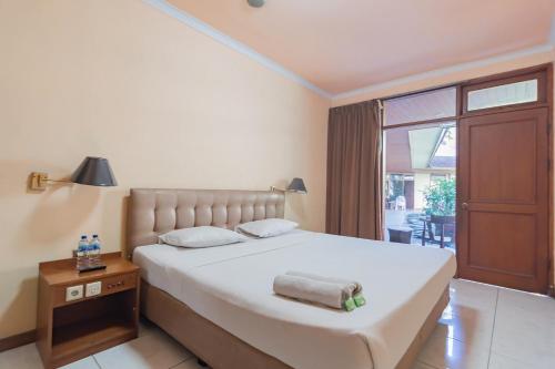 - une chambre avec un grand lit et une grande fenêtre dans l'établissement Dequr Hotel Dipati Ukur Mitra RedDoorz, à Bandung