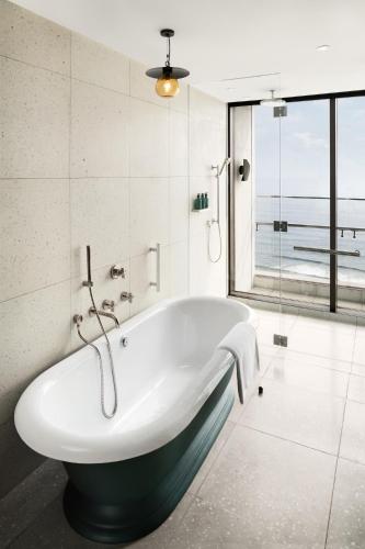 a bath tub in a bathroom with a large window at New World Hoiana Beach Resort in Hoi An