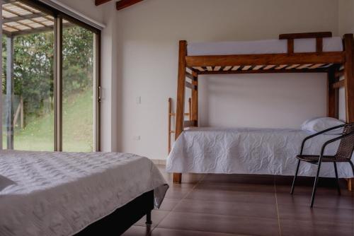 a bedroom with a bed and a chair and a window at Finca en Marinilla in Marinilla