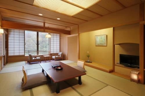 uma sala de estar com uma mesa e uma televisão em Bankokuya em Tsuruoka