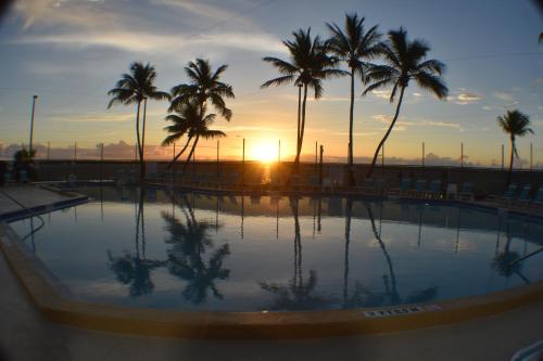 a pool with palm trees in front of a sunset at Pelican's Roost, Waterfront comfort at Venture Out in Cudjoe Key
