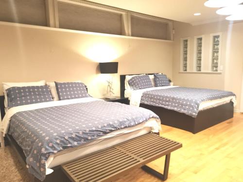 a bedroom with two beds and a bench in it at Van Nest near YVR UBC Downtown in Vancouver