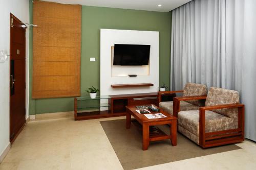 a living room with a tv and a chair and a table at Kuruva Island Resort And Spa - By KABINI BREEZE in Mananthavady
