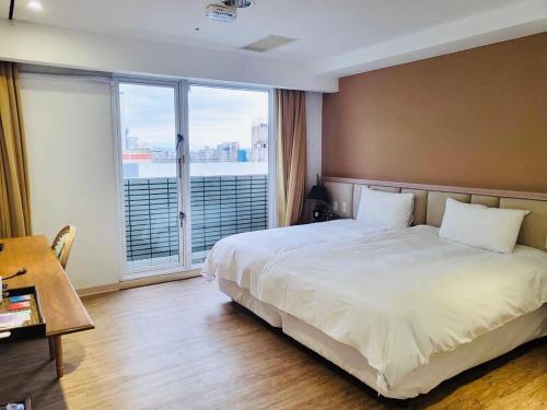 a bedroom with a large bed and a large window at Taichung EnrichLife Hotel in Taichung