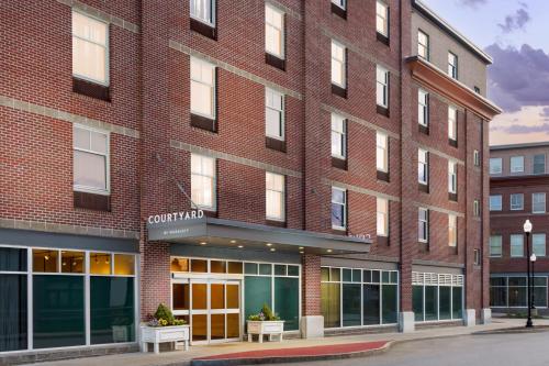 a red brick building with benches in front of it at Courtyard Keene Downtown in Keene