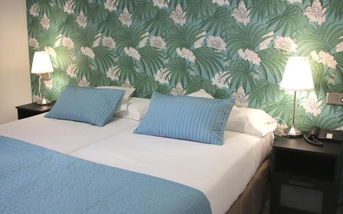 a bedroom with a bed with two blue pillows at Hotel Isla Menor in Dos Hermanas